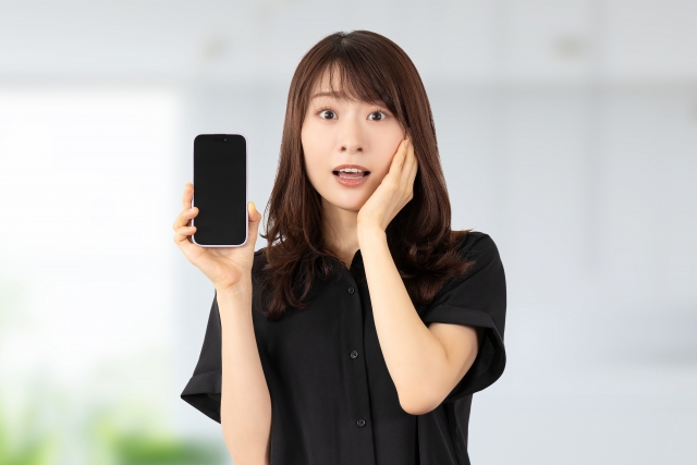 スマホを持って驚く女性