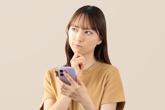 スマホを見て考え事をする女性