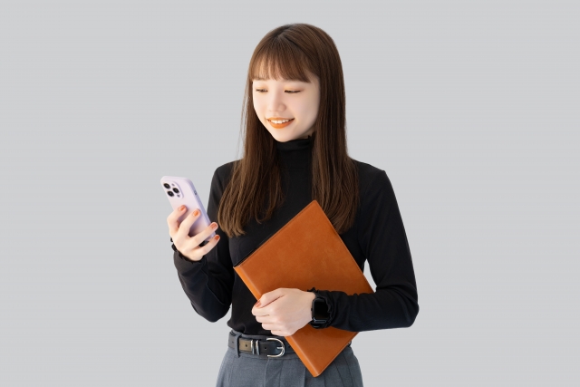 スマホとバインダーを持つ女性